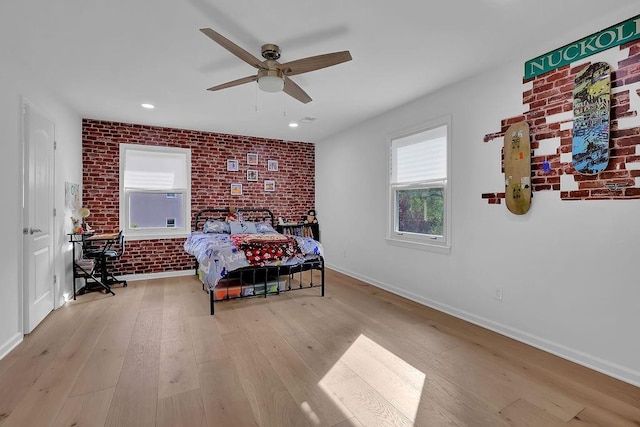 bedroom with ceiling fan, brick wall, and light wood-type flooring