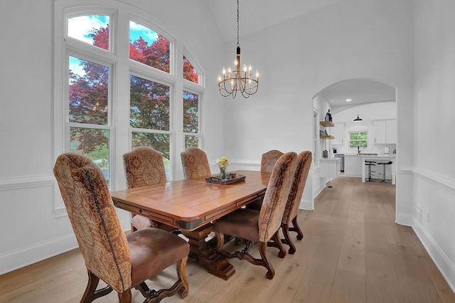 dining space with a towering ceiling, an inviting chandelier, and light hardwood / wood-style floors