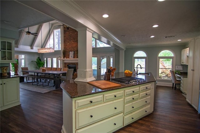 1345 Quail Hollow Dr, Hamilton, GA 31811 - kitchen with green cabinetry, a brick fireplace, a kitchen island, ornamental molding, and stainless steel gas cooktop