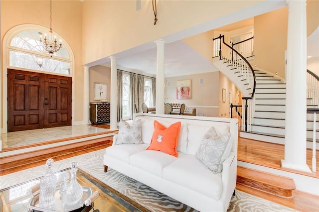 foyer featuring a towering ceiling, a chandelier, ornate columns, and light hardwood / wood-style floors