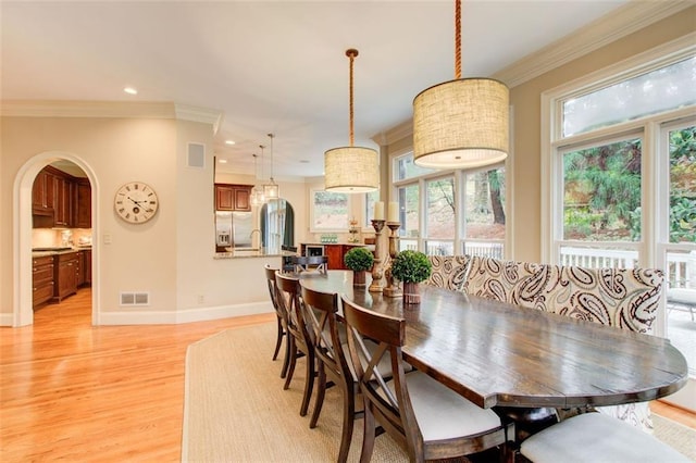 dining room featuring sink, ornamental molding, and light wood-type flooring