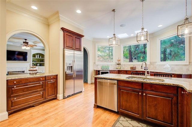 kitchen with sink, pendant lighting, light stone countertops, and appliances with stainless steel finishes