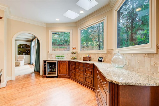 bar featuring light hardwood / wood-style floors, wine cooler, a wealth of natural light, and light stone counters