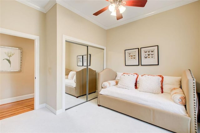 carpeted bedroom with crown molding, a closet, and ceiling fan