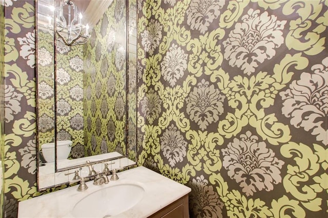 bathroom featuring toilet, a notable chandelier, and vanity