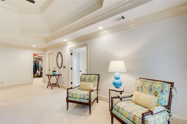 living area featuring ceiling fan, light carpet, ornamental molding, and a raised ceiling