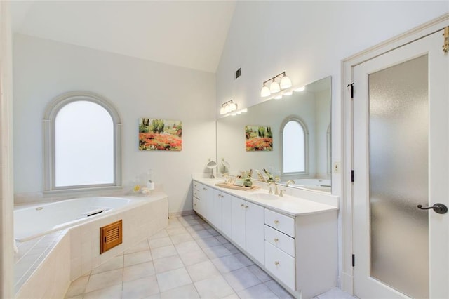 bathroom with a relaxing tiled tub, tile patterned floors, lofted ceiling, and vanity