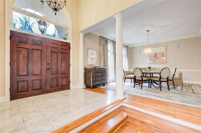 foyer featuring plenty of natural light, ornate columns, and a chandelier