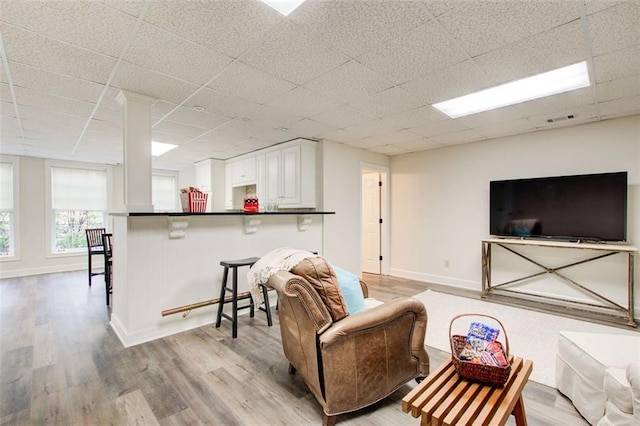 living room with a paneled ceiling and light hardwood / wood-style flooring