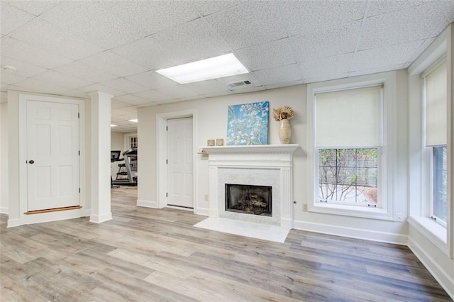 unfurnished living room featuring light wood-type flooring and a paneled ceiling