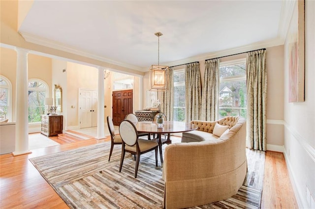 dining area featuring ornamental molding, light hardwood / wood-style floors, plenty of natural light, and ornate columns