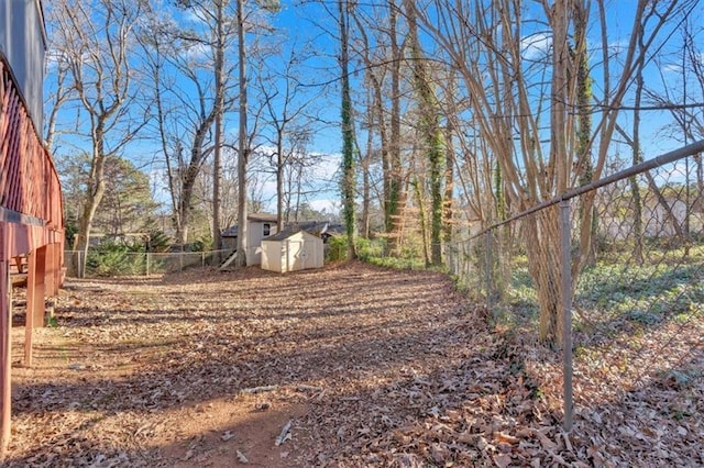 view of yard featuring a shed, fence, and an outdoor structure