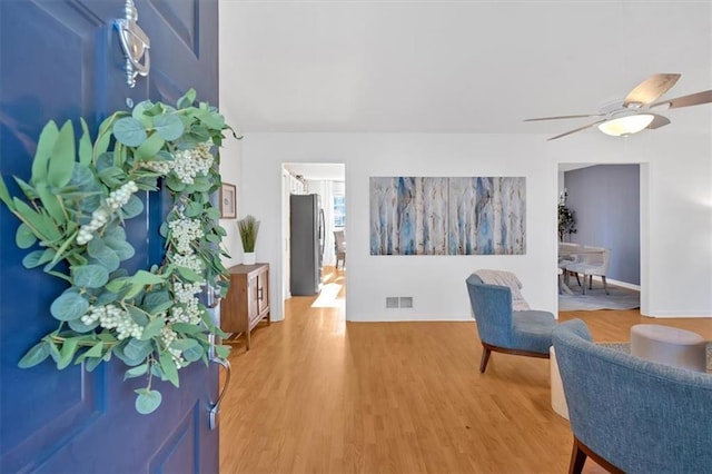 sitting room with baseboards, a ceiling fan, visible vents, and light wood-style floors