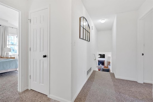 hall featuring light carpet, visible vents, and baseboards