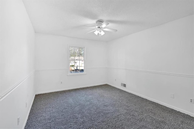 carpeted empty room featuring a textured ceiling, visible vents, a ceiling fan, and baseboards