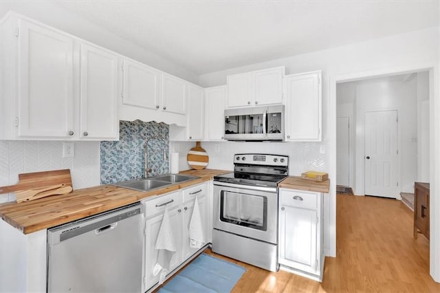 kitchen with stainless steel appliances, light wood-style floors, white cabinets, and a sink