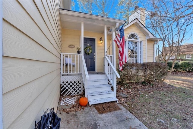 entrance to property featuring a chimney and a porch