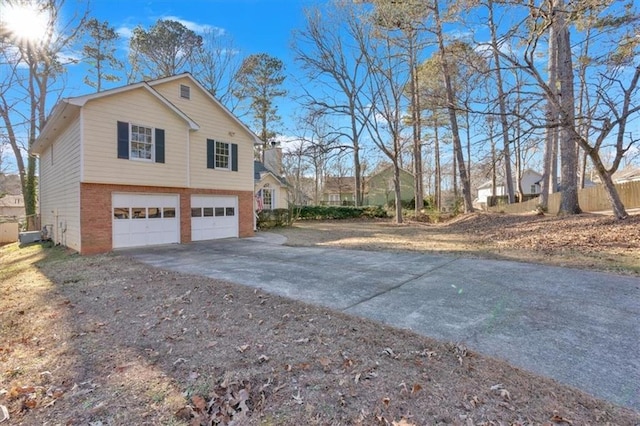 view of home's exterior featuring a garage, driveway, brick siding, and a chimney