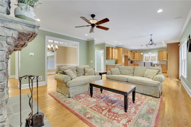 living room featuring crown molding, light hardwood / wood-style flooring, and ceiling fan with notable chandelier