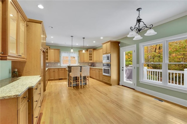 kitchen with decorative backsplash, a kitchen breakfast bar, stainless steel appliances, a center island, and light wood-type flooring