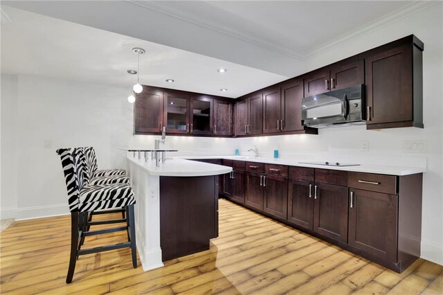 kitchen with a kitchen bar, light hardwood / wood-style flooring, black appliances, pendant lighting, and crown molding