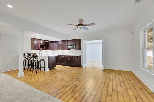 kitchen featuring light hardwood / wood-style floors, crown molding, a kitchen bar, and ceiling fan