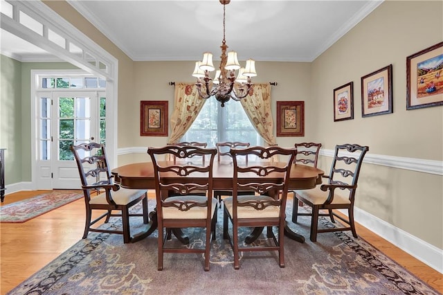 dining area with ornamental molding, a chandelier, wood-type flooring, and a healthy amount of sunlight