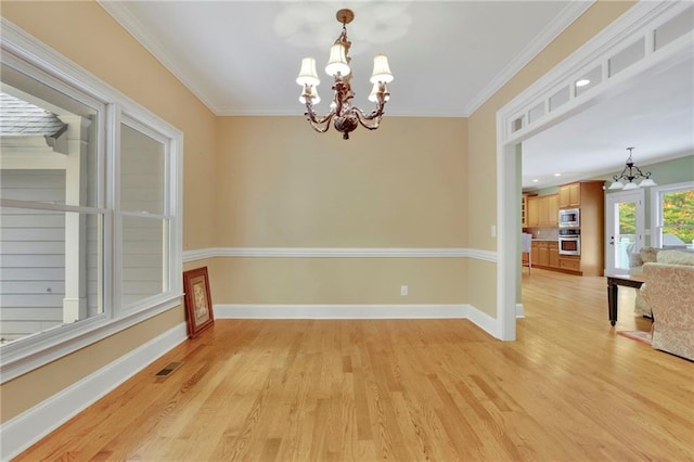 empty room with light hardwood / wood-style floors, ornamental molding, and a chandelier