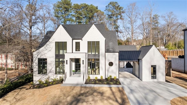 view of front of house featuring metal roof, fence, driveway, and a standing seam roof