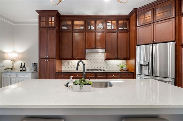 kitchen featuring sink, crown molding, stainless steel appliances, light stone countertops, and backsplash