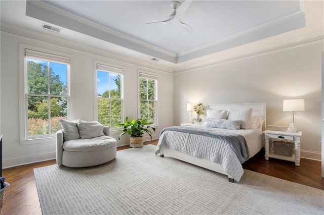 bedroom with hardwood / wood-style floors, crown molding, a raised ceiling, and ceiling fan