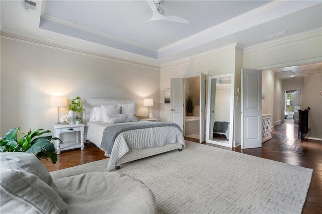 bedroom with crown molding, ensuite bath, a raised ceiling, and ceiling fan