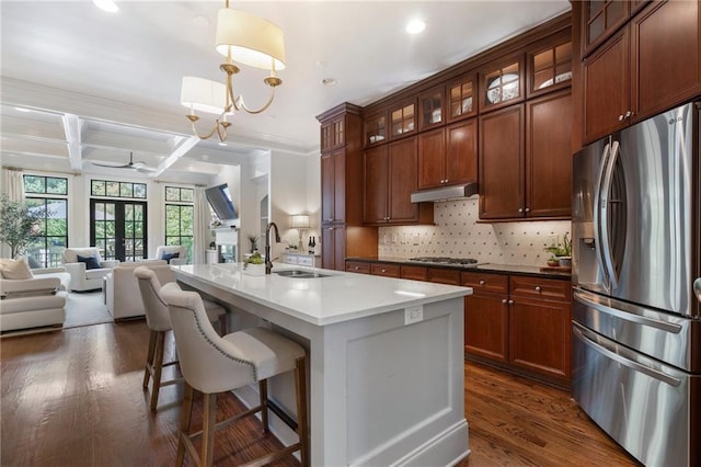 kitchen with a kitchen island with sink, stainless steel appliances, coffered ceiling, decorative backsplash, and decorative light fixtures