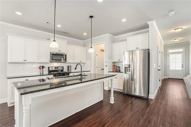 kitchen with a sink, white cabinets, ornamental molding, appliances with stainless steel finishes, and dark wood finished floors