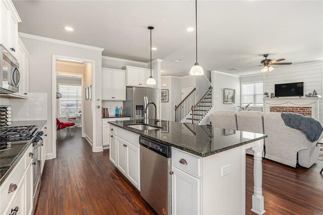 kitchen featuring stainless steel appliances, a wealth of natural light, open floor plan, a sink, and a kitchen breakfast bar