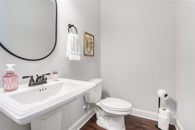 bathroom featuring toilet, a sink, baseboards, and wood finished floors