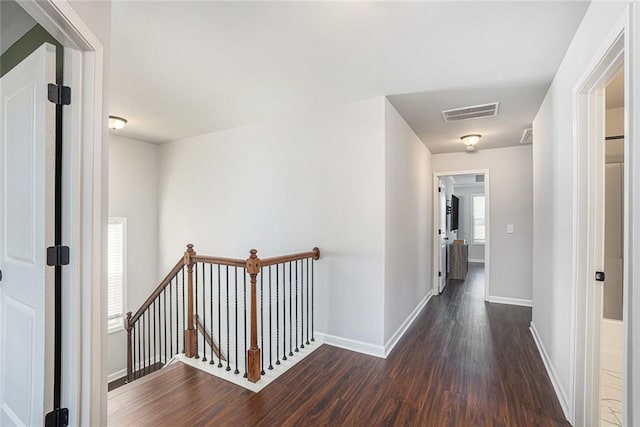 corridor featuring visible vents, wood finished floors, an upstairs landing, and baseboards