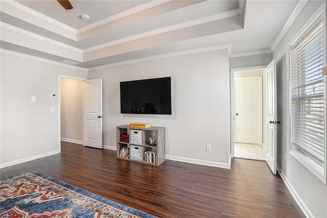 unfurnished living room featuring a tray ceiling, crown molding, baseboards, and wood finished floors