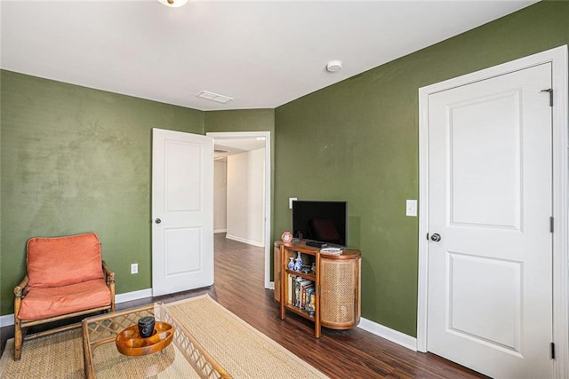 living area featuring dark wood-style floors, visible vents, and baseboards