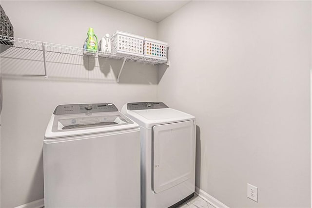 clothes washing area featuring laundry area, baseboards, marble finish floor, and washing machine and clothes dryer