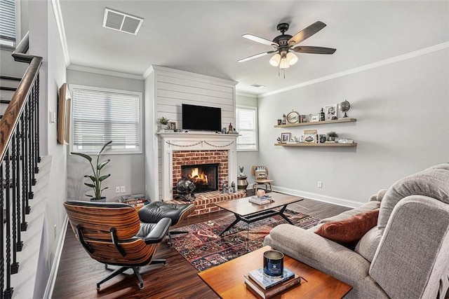 living area with visible vents, a brick fireplace, wood finished floors, baseboards, and stairs