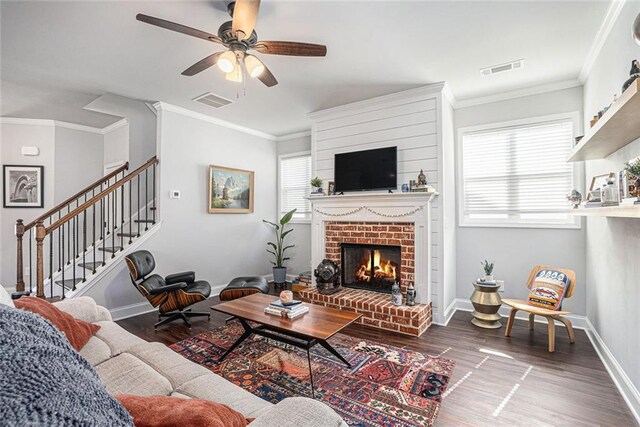 living area featuring a brick fireplace, stairs, baseboards, and wood finished floors