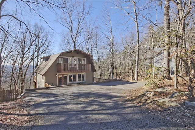 view of front facade with fence, aphalt driveway, and a gambrel roof