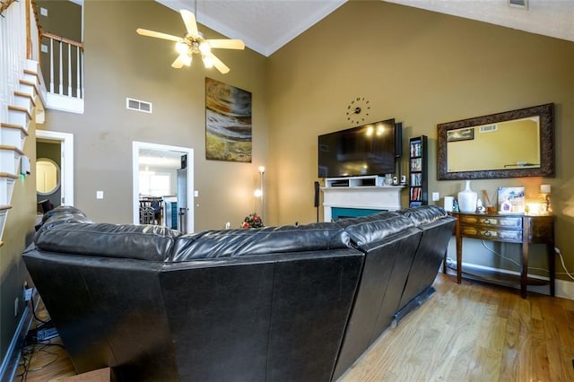 living area with visible vents, high vaulted ceiling, wood finished floors, a fireplace, and ceiling fan