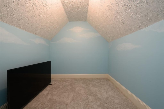 additional living space featuring vaulted ceiling, a textured ceiling, baseboards, and carpet floors