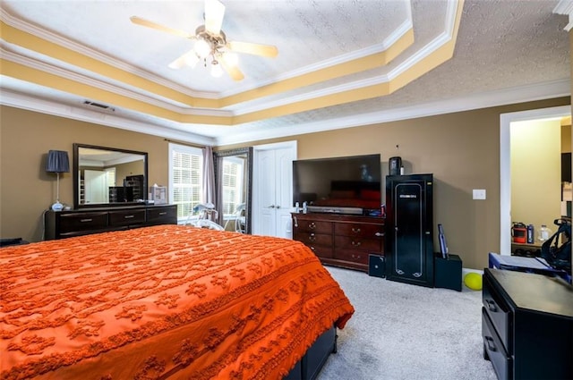 bedroom with visible vents, ornamental molding, a tray ceiling, a textured ceiling, and carpet floors