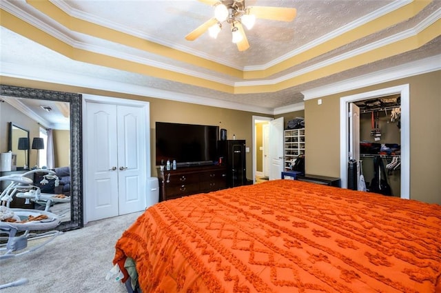 bedroom featuring crown molding, carpet floors, a textured ceiling, a raised ceiling, and a ceiling fan