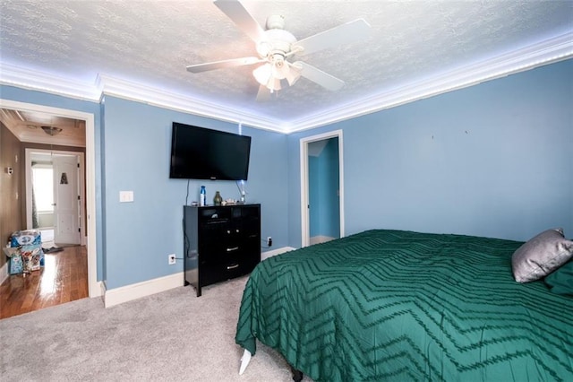 carpeted bedroom with ornamental molding, a textured ceiling, baseboards, attic access, and ceiling fan