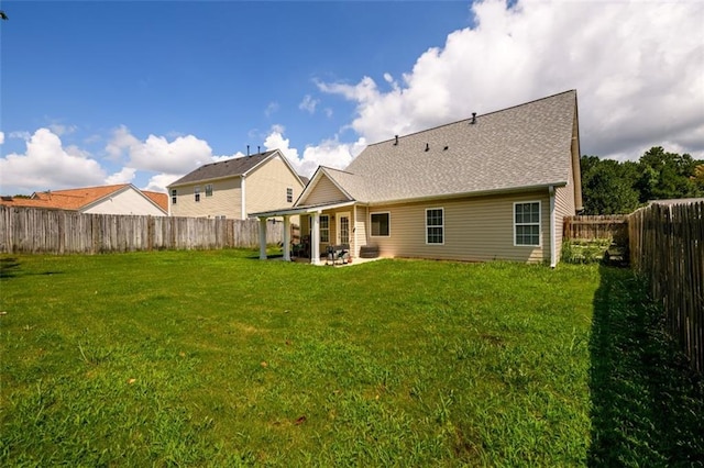 rear view of house with a fenced backyard, a patio area, and a yard