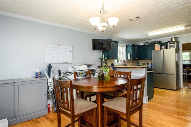 dining room featuring visible vents, an inviting chandelier, crown molding, and light wood-style floors